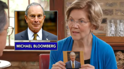 Elizabeth Warren holds up a picture of Mike Bloomberg during 