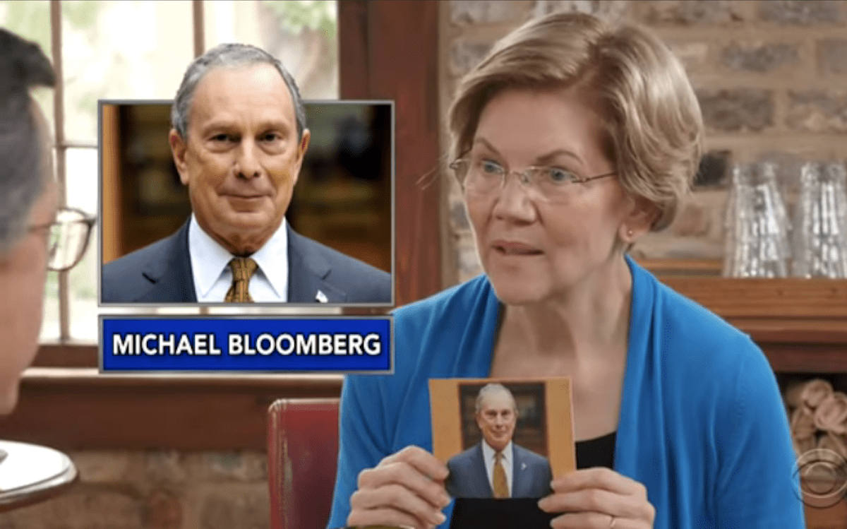 Elizabeth Warren holds up a picture of Mike Bloomberg during "Name That Billionaire" with Stephen Colbert