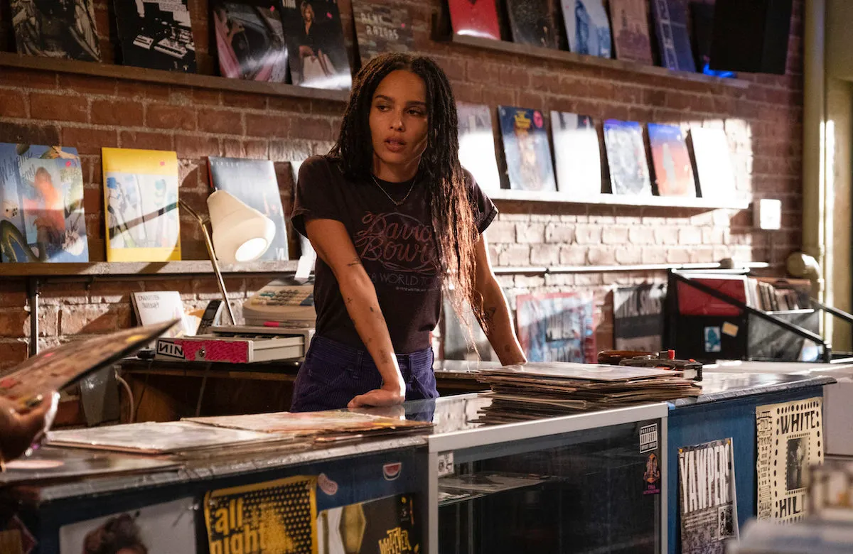 High Fidelity's Rob (Zoe Kravitz) leans on the counter of her record shop.