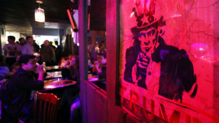 A sign of Uncle Sam reading 'Dump Trump' is lit in ominous red.