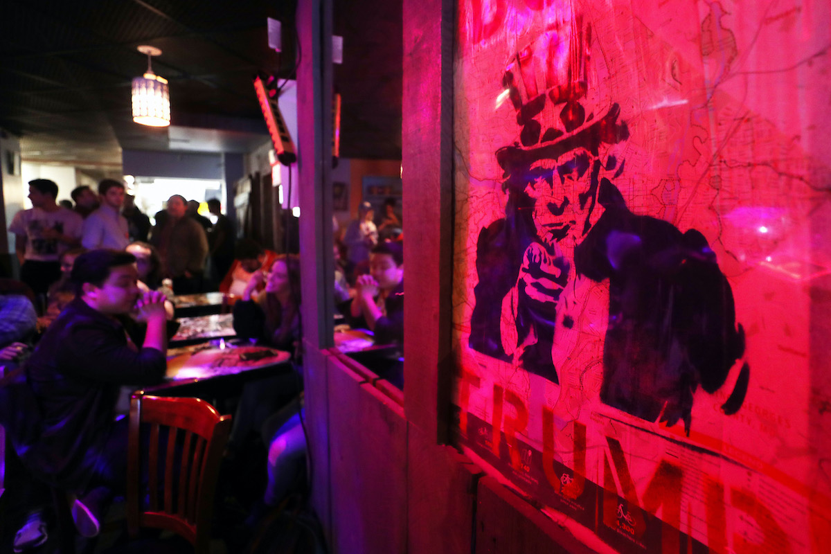 A sign of Uncle Sam reading 'Dump Trump' is lit in ominous red.