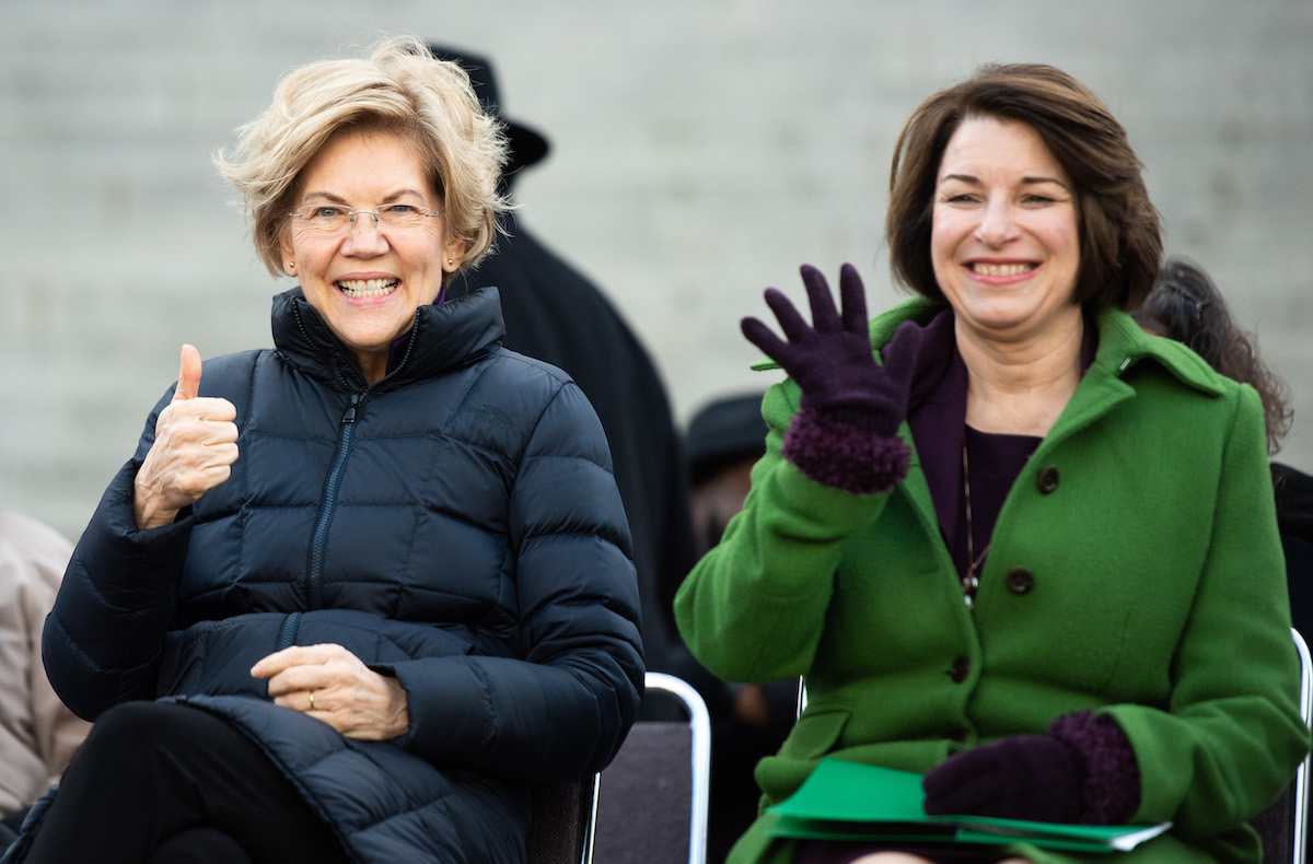 Democratic presidential candidates, Sen. Elizabeth Warren (D-MA), left, and Sen. Amy Klobuchar (D-MN) gesture to the crowd during the King Day at the Dome rally