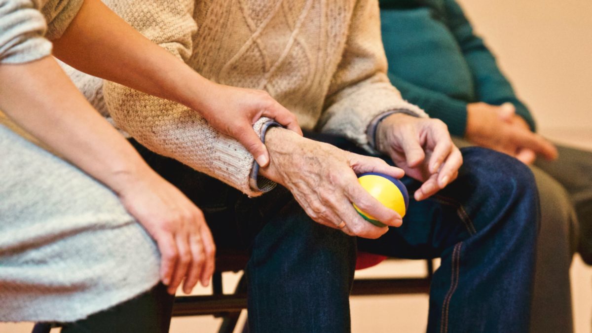 a younger person holds and elderly person's hands