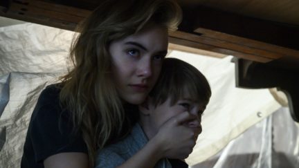 Kinsey covers Bode's mouth as they hide in Netflix's Locke and Key.