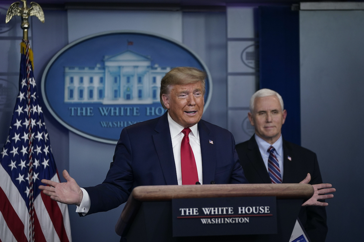 Donald Trump speaks as Vice President Mike Pence looks on during a briefing on the coronavirus pandemic in the press briefing room of the White House