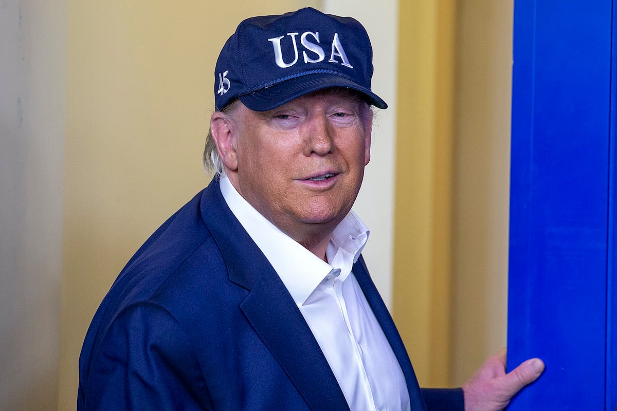 Donald Trump smirks in a USA baseball cap.