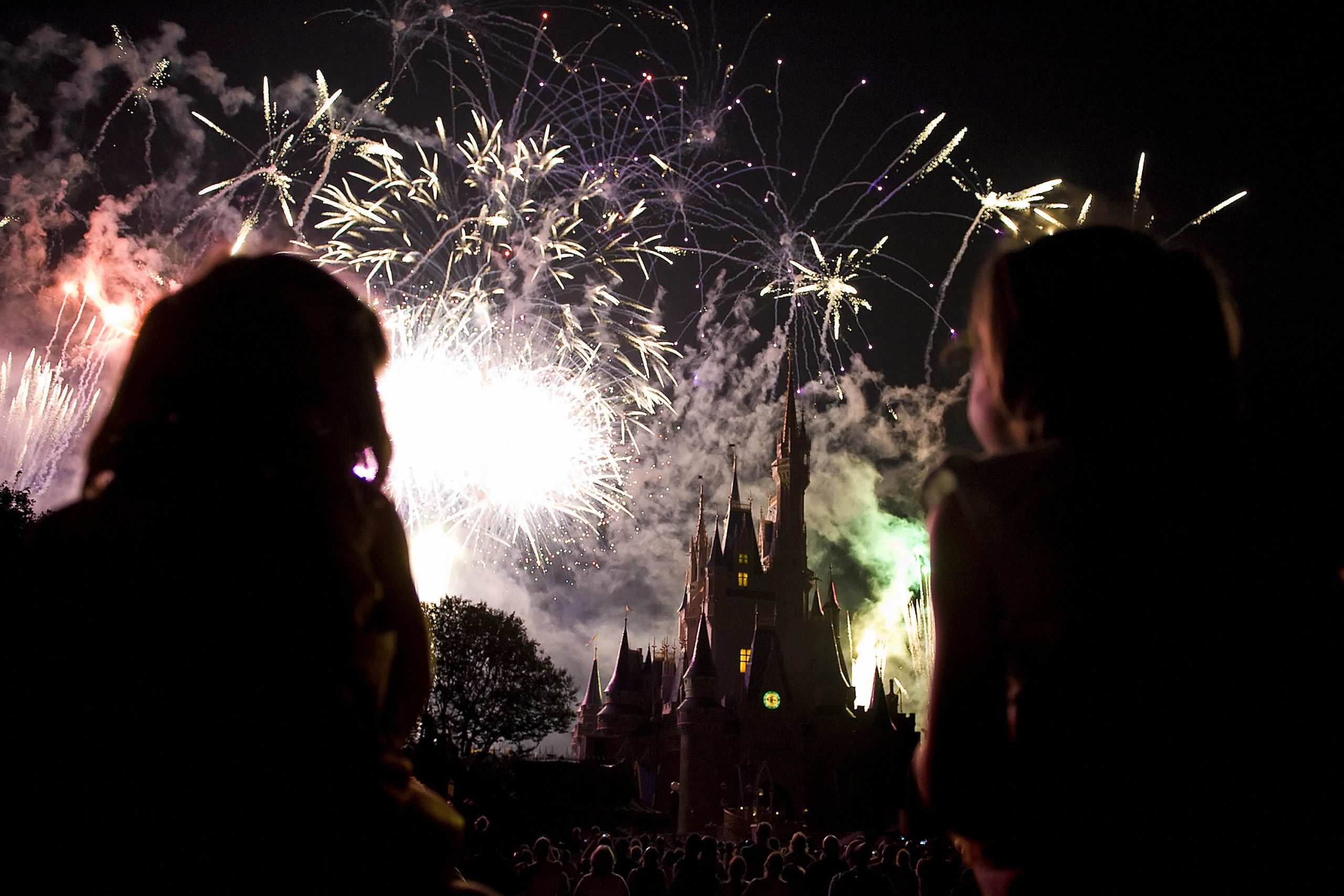 Two children watch the fireworks display as it explodes over Cinderella's Castle at Disney World's Magic Kingdom in Orlando, Florida, May 7, 2008. The complex is reportedly the most visited and largest recreational resort in the world, containing four theme parks, two water parks, twenty-three themed hotels, and numerous shopping, dining, entertainment and recreation venues. Disney World opened on October 1, 1971. AFP PHOTO/Jim WATSON (Photo credit should read JIM WATSON/AFP via Getty Images)