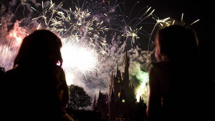 Two children watch the fireworks display as it explodes over Cinderella's Castle at Disney World's Magic Kingdom in Orlando, Florida, May 7, 2008. The complex is reportedly the most visited and largest recreational resort in the world, containing four theme parks, two water parks, twenty-three themed hotels, and numerous shopping, dining, entertainment and recreation venues. Disney World opened on October 1, 1971. AFP PHOTO/Jim WATSON (Photo credit should read JIM WATSON/AFP via Getty Images)
