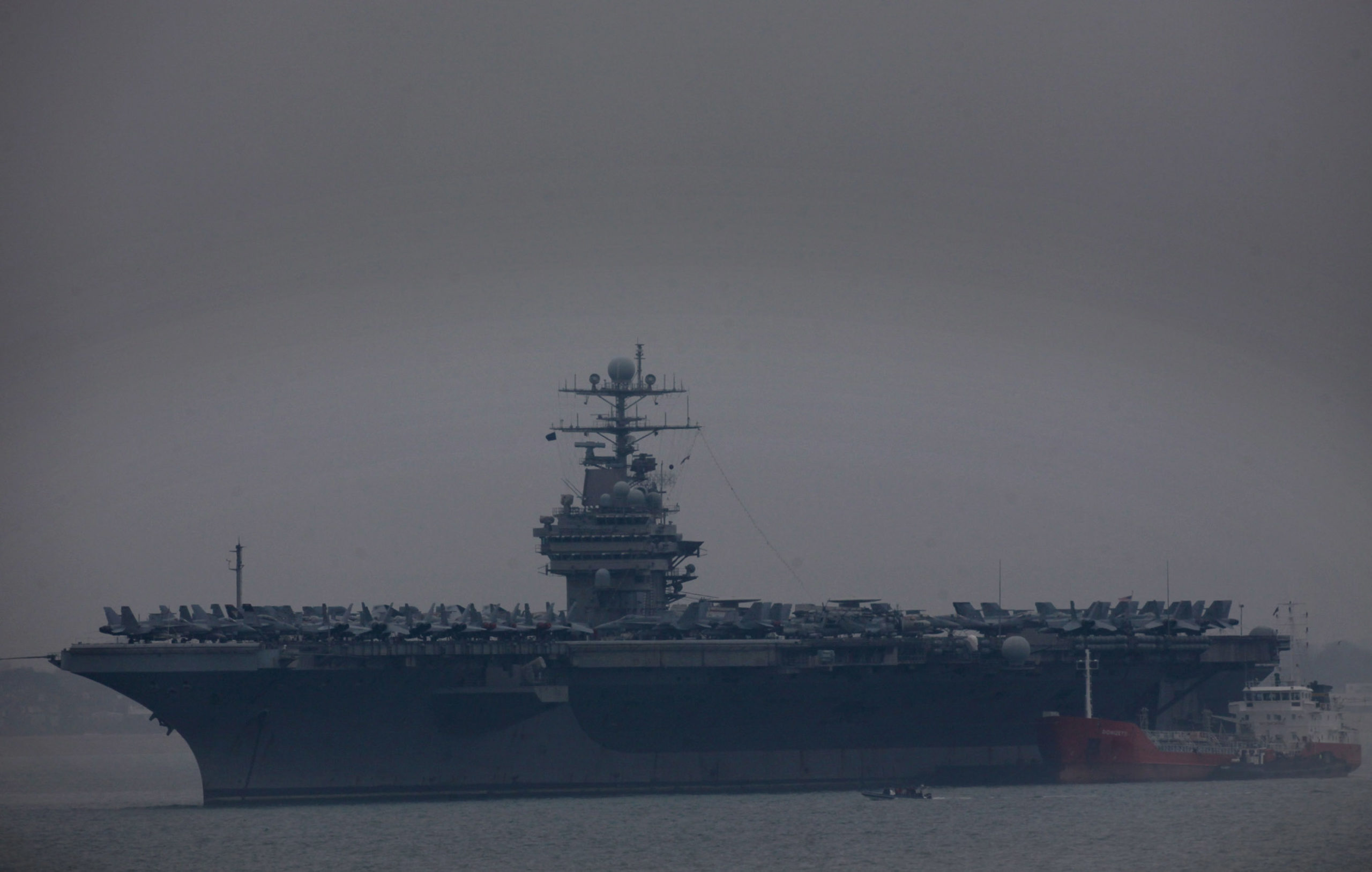 PORTSMOUTH, ENGLAND - APRIL 06: People stand on the deck of the USS Theodore Roosevelt anchored off Stokes Bay on April 6, 2009 in Portsmouth, England. The 88,000-tonne US aircraft carrier, carrying nearly 5,000 sailors, arrived in the Solent having spent the last five months supporting ground forces in Afghanistan. (Photo by Matt Cardy/Getty Images)