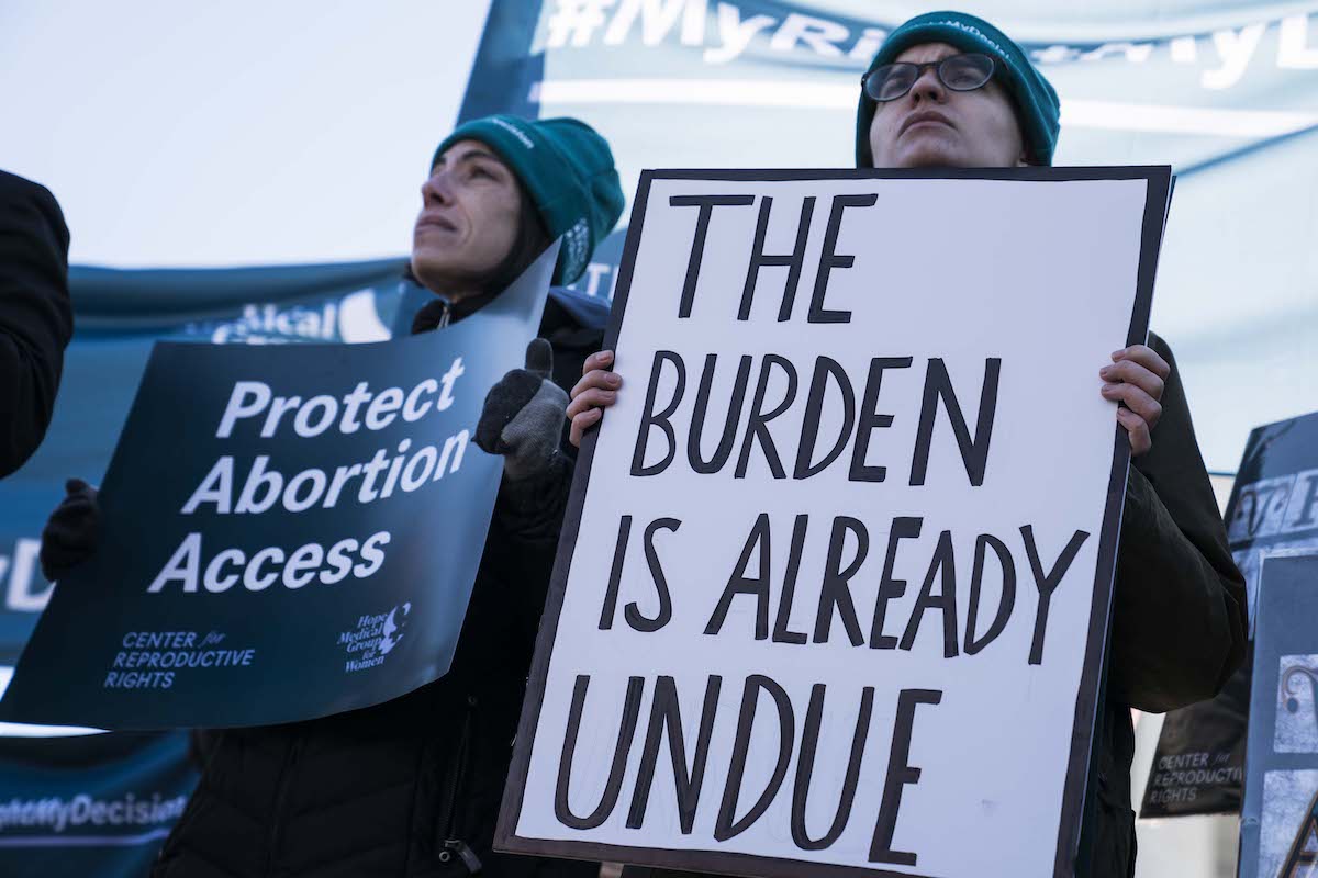 Abortion rights demonstrators hold pro-choice sign reading "the burden is already undue"