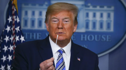 Donald Trump holds up swabs as he speaks at the daily coronavirus briefing at the White House
