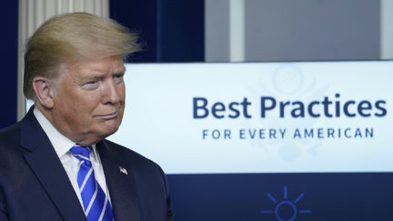 Donald Trump stands in front of a sign reading 'Best Practices for every American' during press briefing.