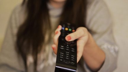 Woman holds a television remote.