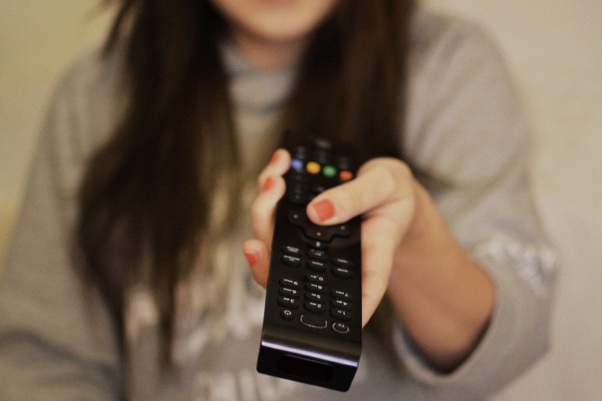 Woman holds a television remote.
