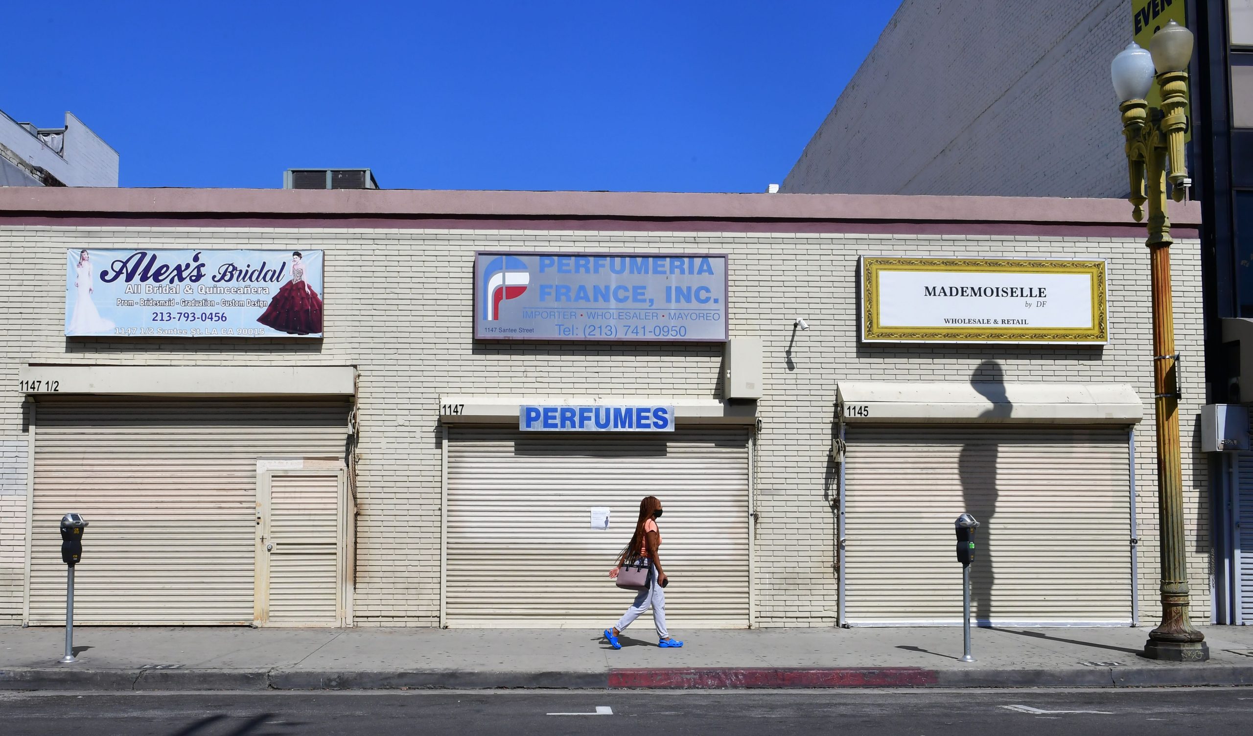 A woman walks past closed shopfronts in what would be a normally busy fashion district in Los Angeles, California on May 4, 2020. - California governor Gavin Newsom earlier today announced the gradual reopening of the state later this week as dismal US employment figures are expected with the release of figures Friday May 8 for April's US jobs report, as 30 million Americans filed for unemployment in the last six weeks. (Photo by Frederic J. BROWN / AFP) (Photo by FREDERIC J. BROWN/AFP via Getty Images)
