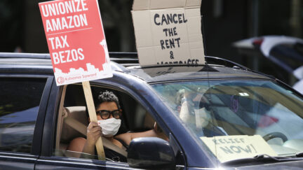 People drive around the block with anti-Jeff Bezos signs as they participate in a 