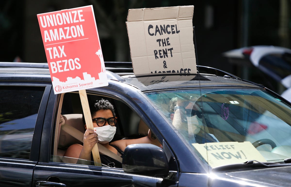People drive around the block with anti-Jeff Bezos signs as they participate in a "car caravan" protest