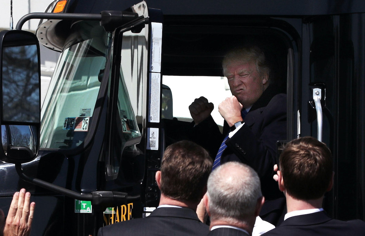 Trump pretends to drive a big boy truck.