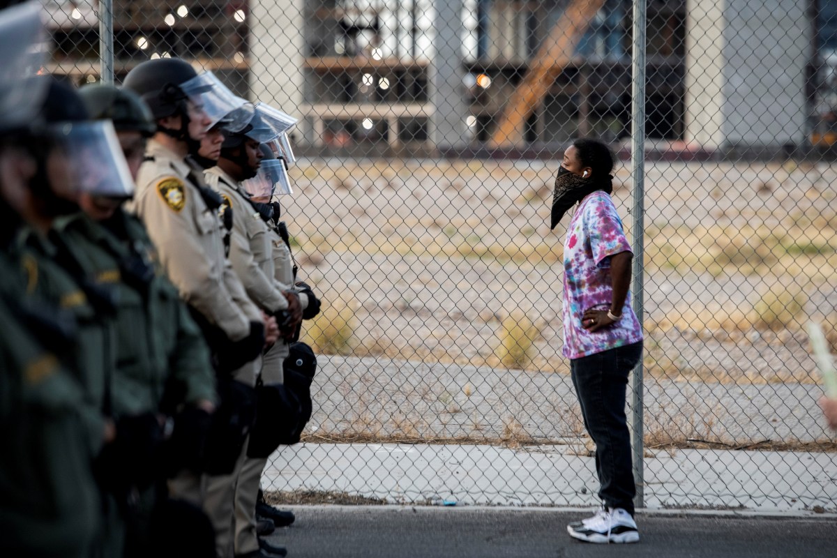 TOPSHOT - A woman stands in front of Police officers, on June 1, 2020, in downtown Las Vegas, as they take part in a "Black lives matter" rally in response to the recent death of George Floyd, an unarmed black man who died while in police custody. - Thousands of National Guard troops patrolled major US cities after five consecutive nights of protests over racism and police brutality that boiled over into arson and looting, sending shock waves through the country. The death Monday of an unarmed black man, George Floyd, at the hands of police in Minneapolis ignited this latest wave of outrage in the US over law enforcement's repeated use of lethal force against African Americans -- this one like others before captured on cellphone video. (Photo by Bridget BENNETT / AFP) (Photo by BRIDGET BENNETT/AFP via Getty Images)