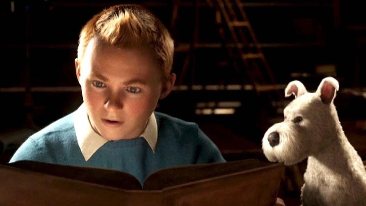 Tintin and his dog look at a book with wonder.