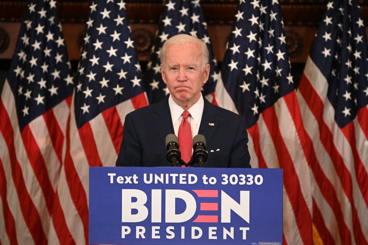 Joe Biden stands at a podium in front of American flags.