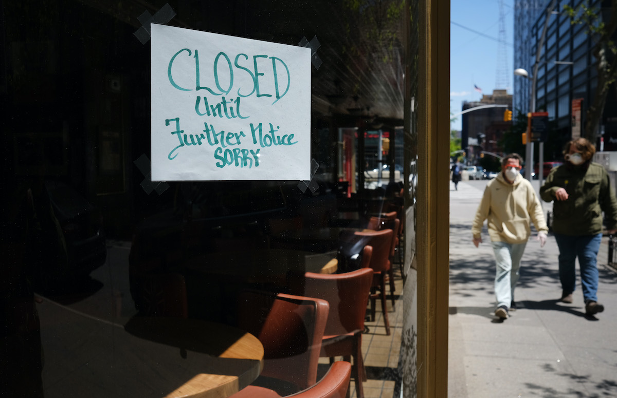 People walk through a shuttered business district