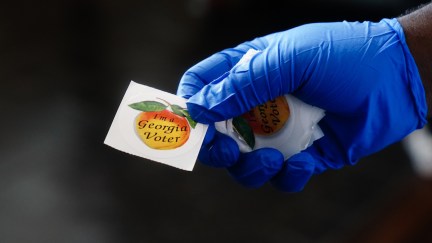 A gloved polling place worker holds an 