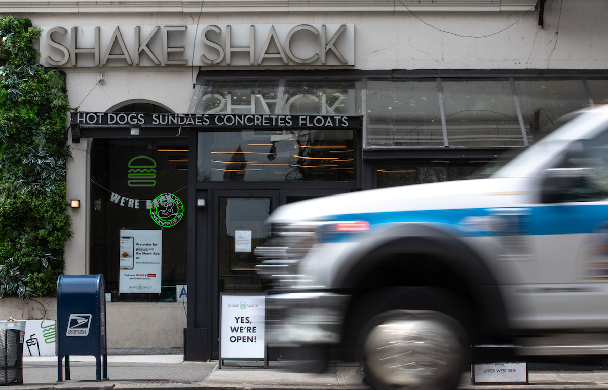 An ambulance drives past a Shake Shack restaurant