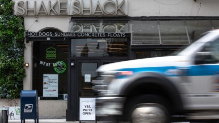 An ambulance drives past a Shake Shack restaurant