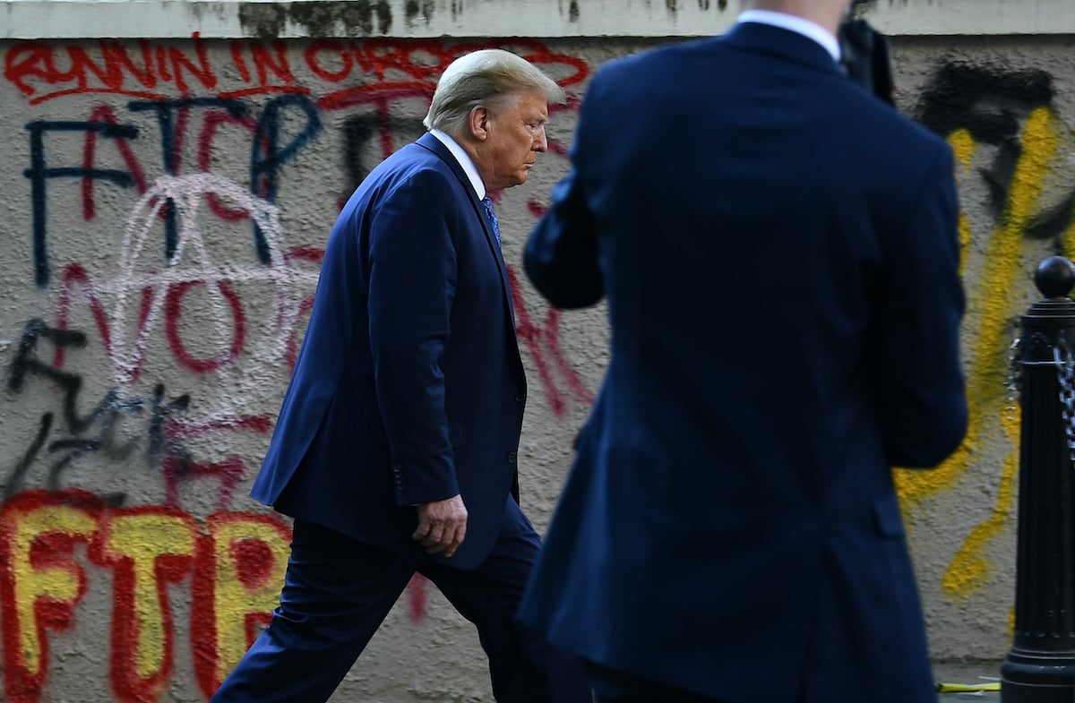 Donald Trump walks past graffiti back to the White House escorted by the Secret Service