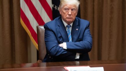 Donald Trump sits with his arms crossed.