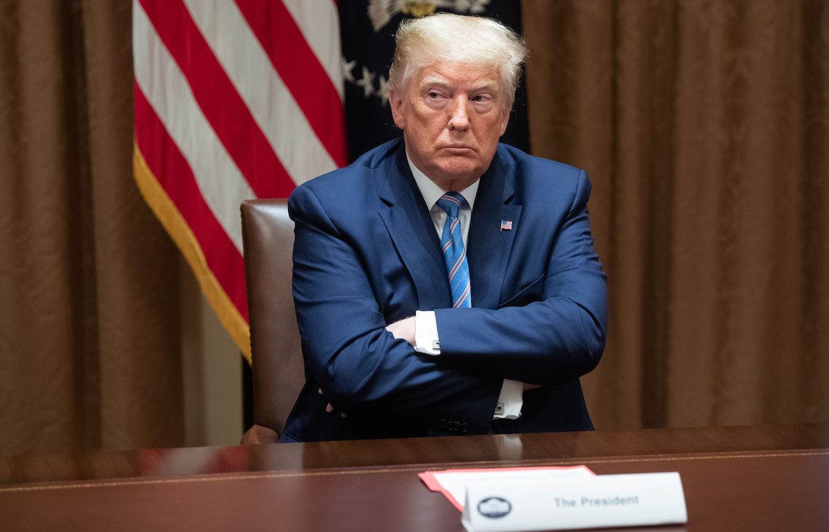 Donald Trump sits with his arms crossed.