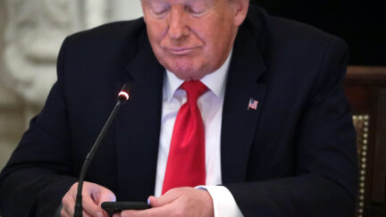 Trump looks at his phone.