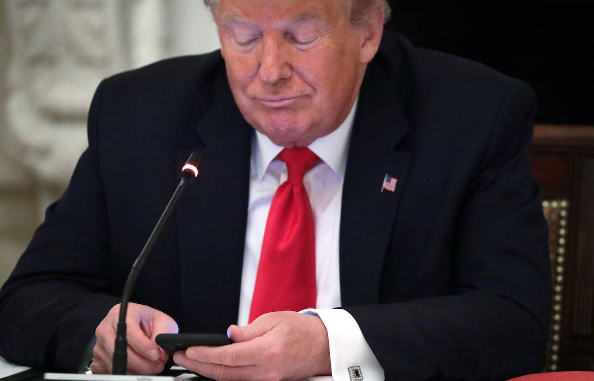 Trump looks at his phone.