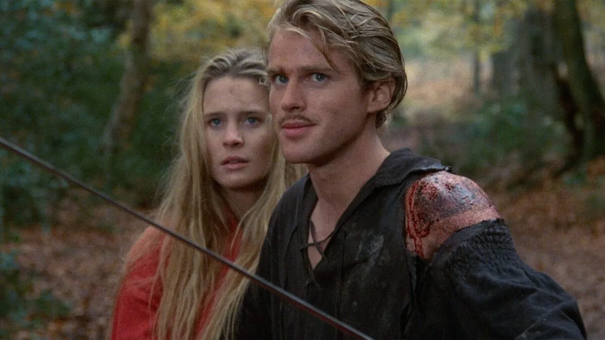 A white man stands protectively of a white woman in the forest, both wearing medieval clothing in "The Princess Bride"
