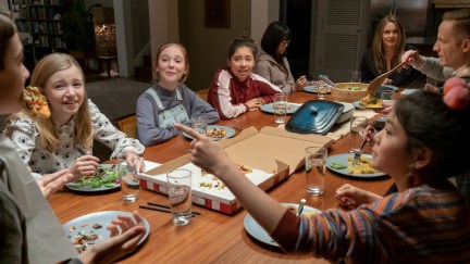 The cast of the Baby-Sitters Club gather around a dinner table.
