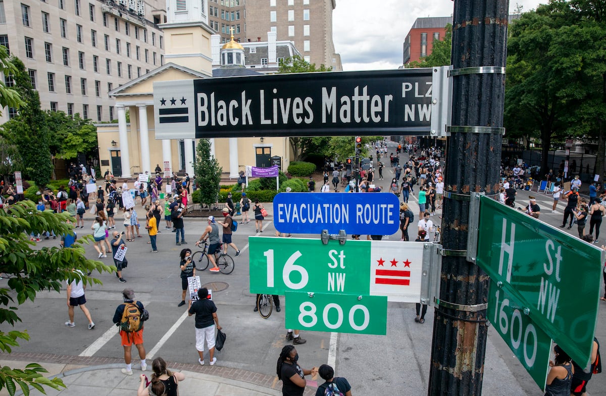 People walk near 16th and H street after volunteers, with permission from the city, painted "Black Lives Matter" on the street near the White House