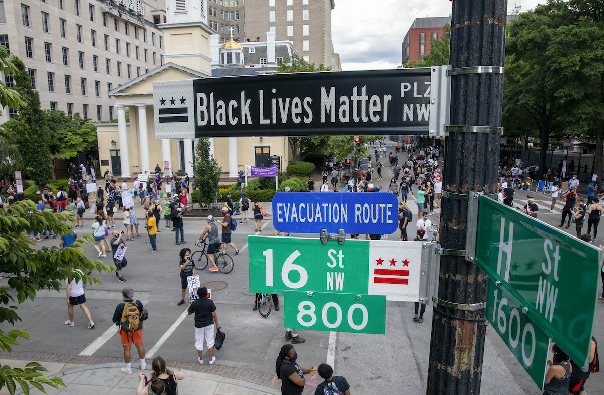 People walk near 16th and H street after volunteers, with permission from the city, painted "Black Lives Matter" on the street near the White House