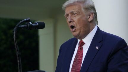 Donald Trump yells into a microphone at a press conference/illegal campaign rally.
