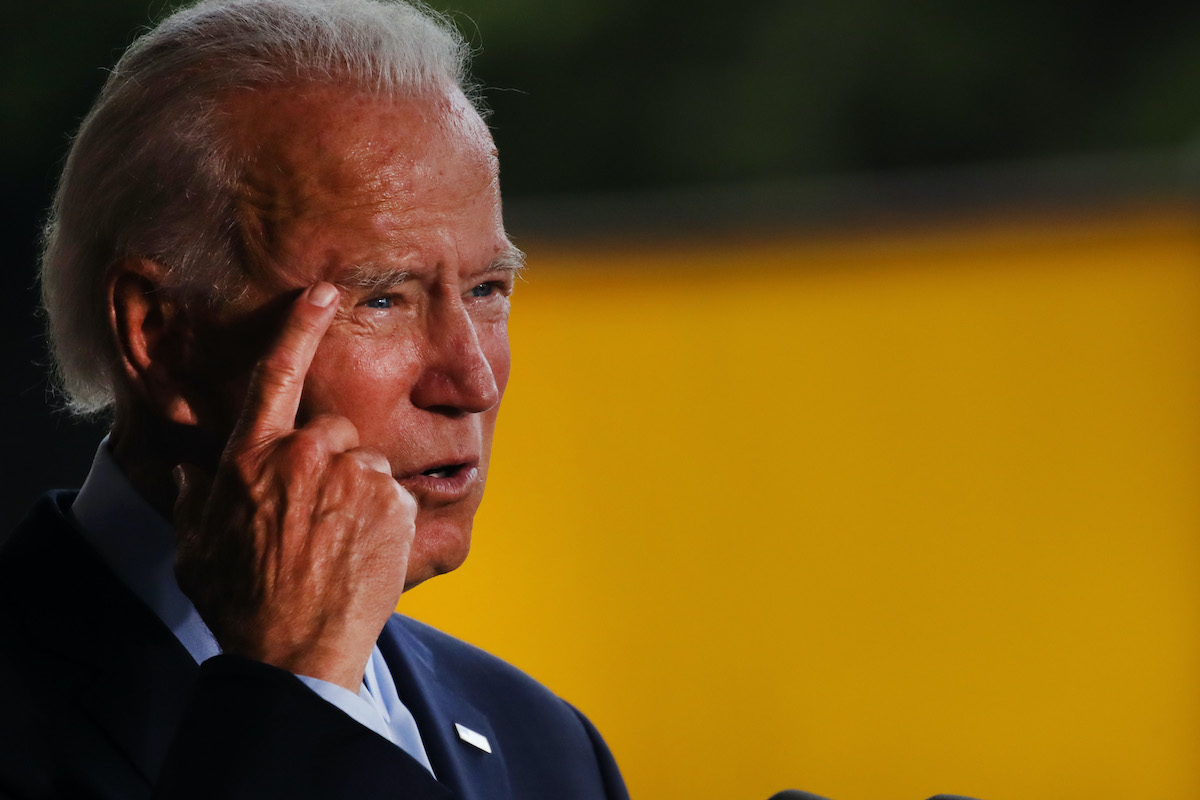 Joe Biden points to his temple while giving a speech.