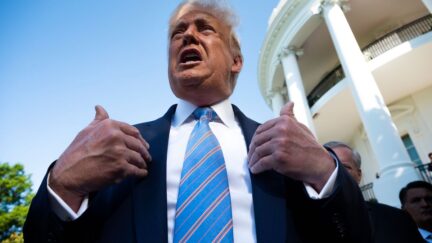 Donald Trump gestures towards himself, speaking to reporters.