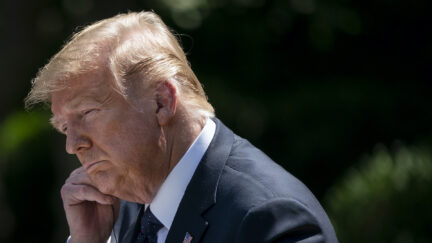 Donald Trump looks sad while appearing to touch his face.