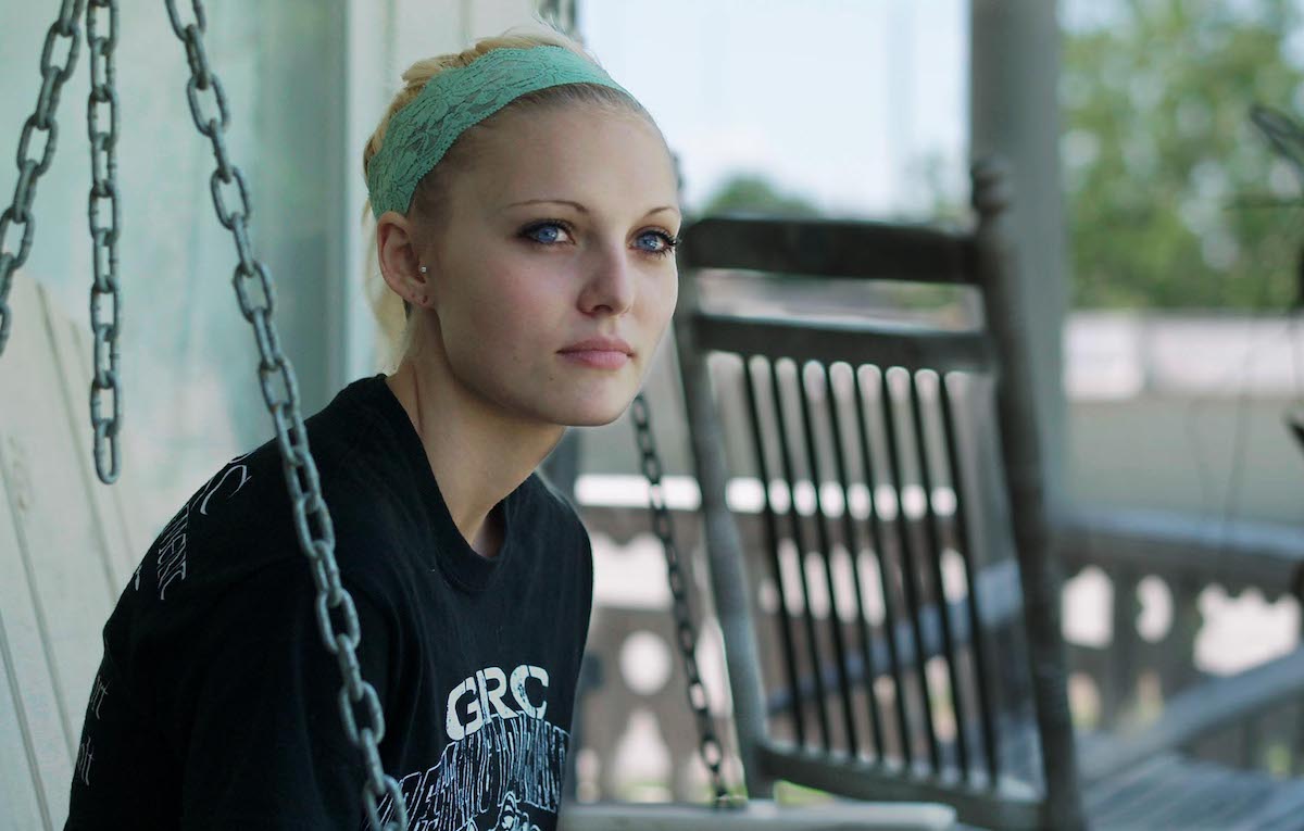Daisy Coleman sits on her porch in a still from Audrie & Daisy.