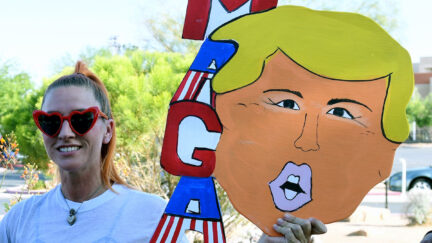 A Trump supporter holds a homemade MAGA sign shaped like Trump's head