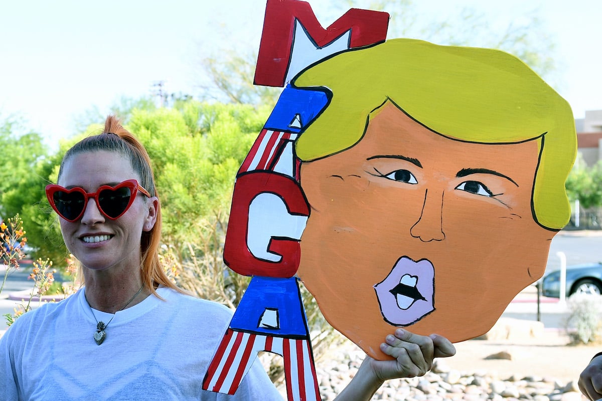 A Trump supporter holds a homemade MAGA sign shaped like Trump's head