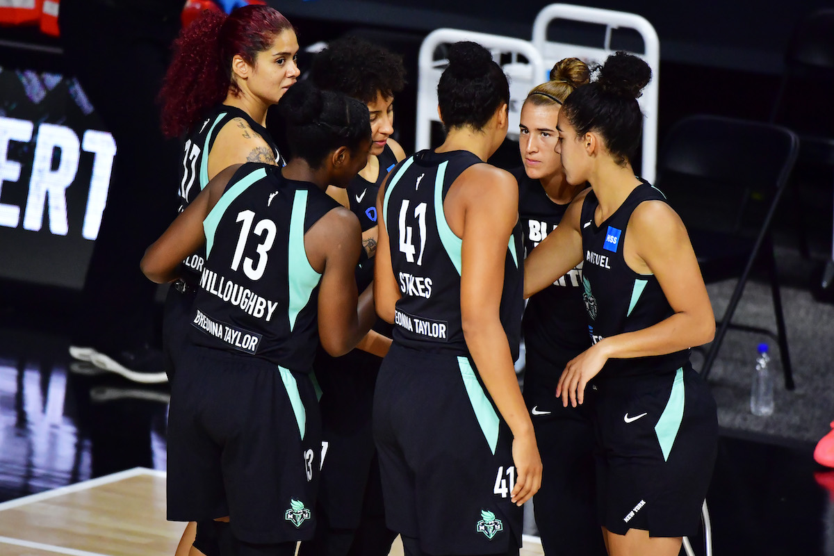 The New York Liberty starters huddle before a game, wearing jerseys bearing Breonna Taylor's name.