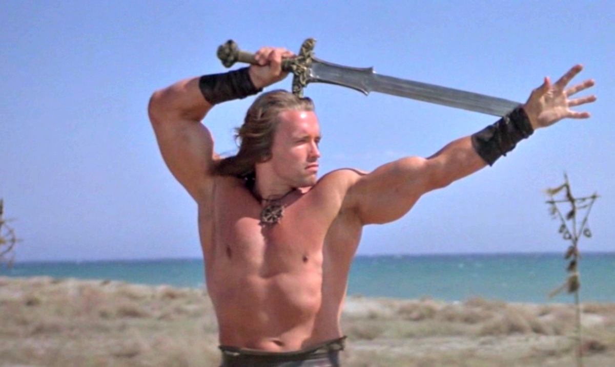 Arnold Schwarzenegger wielding a sword on the beach in 'Conan the Barbarian'