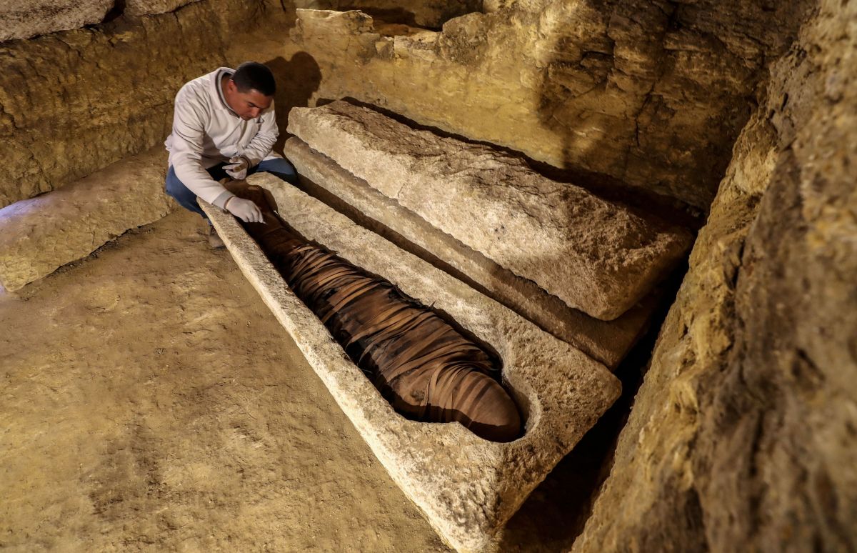 An Egyptian archeologist inspects a mummy in a limestone sarcophagus discovered along many finds in 3000-year-old communal tombs dedicated to high priests, in Al-Ghoreifa in Tuna al-Jabal in the Minya governorate, on January 30, 2020. - Egypt's antiquities ministry unveiled 16 tombs of ancient high priests containing 20 sarcophagi, including one dedicated to the sky god Horus, discovered at the archaeological site, about 300 kilometres (186 miles) south of Cairo. The shared tombs were dedicated to high priests of the god Djehuty and senior officials, from the Late Period, the ministry said. (Photo by Mohamed el-Shahed / AFP) (Photo by MOHAMED EL-SHAHED/AFP via Getty Images)