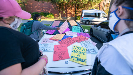 Demonstrators leave signs over a car as they march in protest