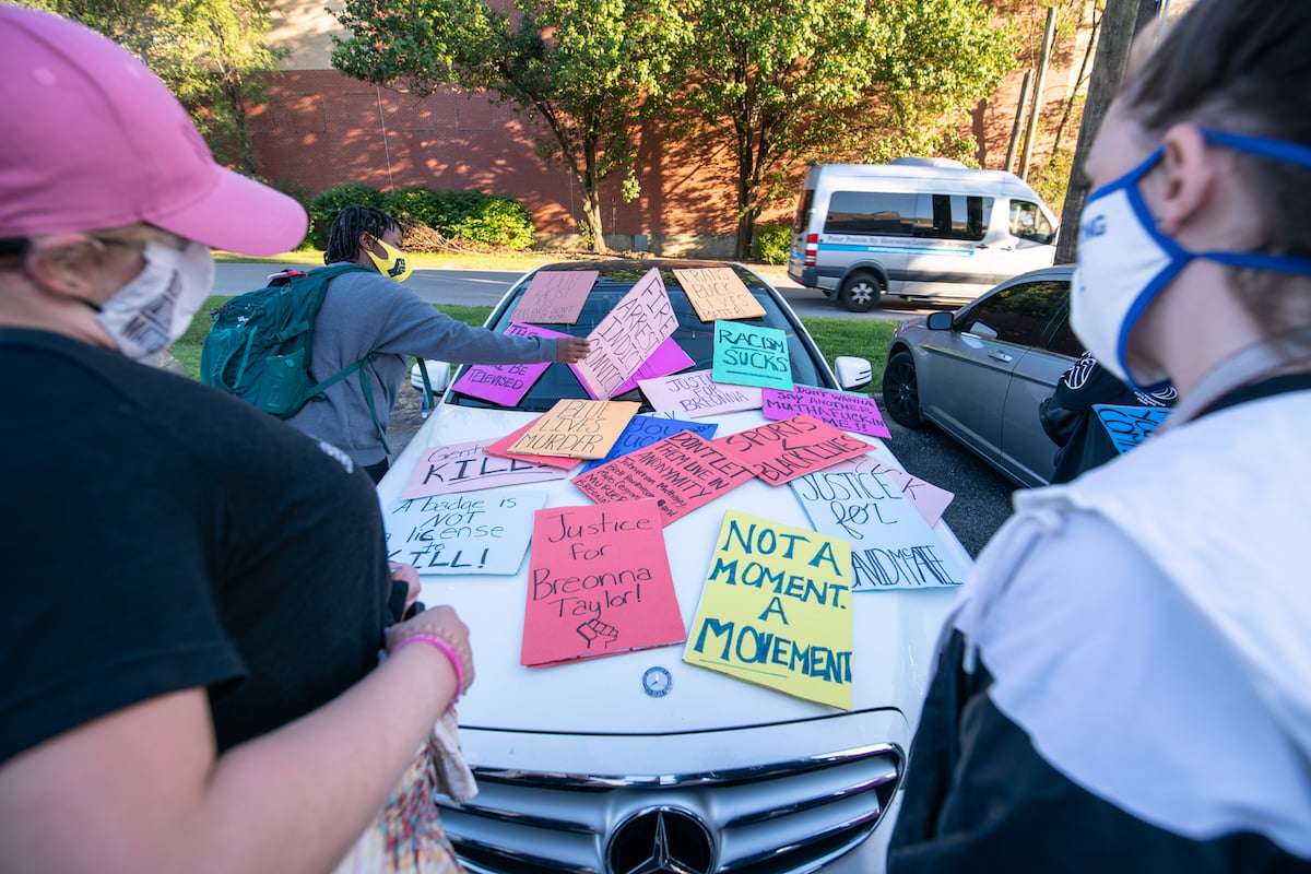 Demonstrators leave signs over a car as they march in protest
